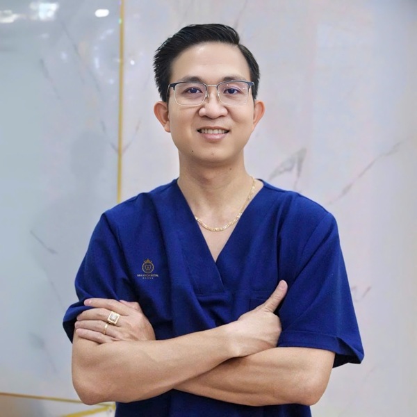 The individual presented in the clinic's publicly available staffing imagery as the clinician working at Metal Dental Clinic, photographed in clinic scrubs bearing the Metal Dental logo. The image is reproduced here for the purpose of the question that follows: this person does not visibly appear as the operator in the procedure footage that the clinic and its facilitator have published publicly and that is analysed in Categories 1, 2, and 3 above. Whether the operators in that footage are themselves registered Vietnamese dental practitioners, registered for the procedures shown, or registered at this clinic, is the question this section names.