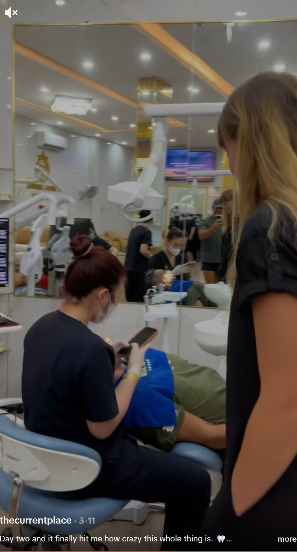 Clinical staff member using a personal mobile phone while wearing treatment gloves during a patient procedure. This is a direct infection control breach: gloves that have contacted the patient's oral environment are now contacting a personal device and then returning to the patient. This is a basic and non-negotiable infection control failure. The patient in the chair cannot see this happening. The facilitator filming this footage clearly could see it — and did not intervene. That is not a moral failure on her part. She is not a dentist or a healthcare practitioner. She almost certainly did not know it was dangerous. That is precisely the problem with routing patients through an unqualified booking agent: the person responsible for the patient's experience has no clinical training to recognise when something has gone wrong.